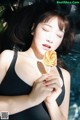 A woman in a black bathing suit holding a lollipop.