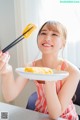 A woman holding a plate of food with chopsticks in her hand.