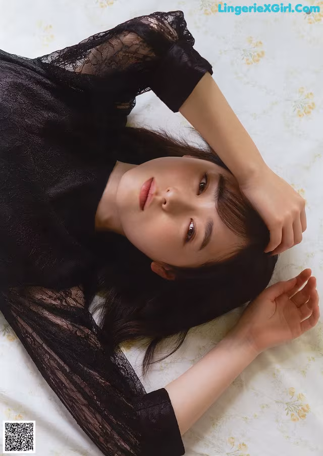 A woman laying on top of a bed in a black dress.