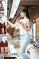 A woman standing in front of a refrigerator holding a bottle of soda.