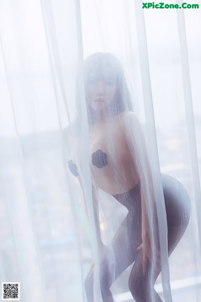 A woman in a black lingerie posing in front of a window.