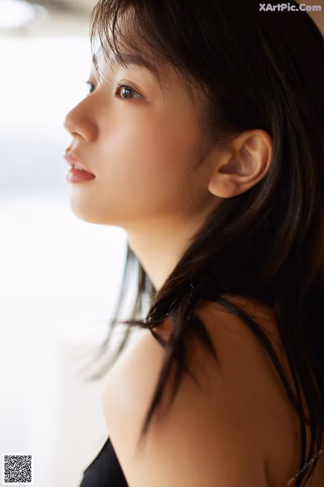 A woman with long black hair looking out a window.