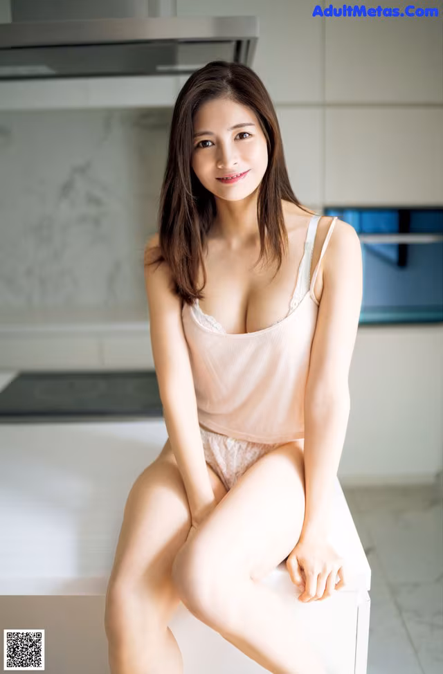 A woman sitting on top of a white box in a kitchen.