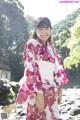 A woman in a pink and white kimono standing in a stream.