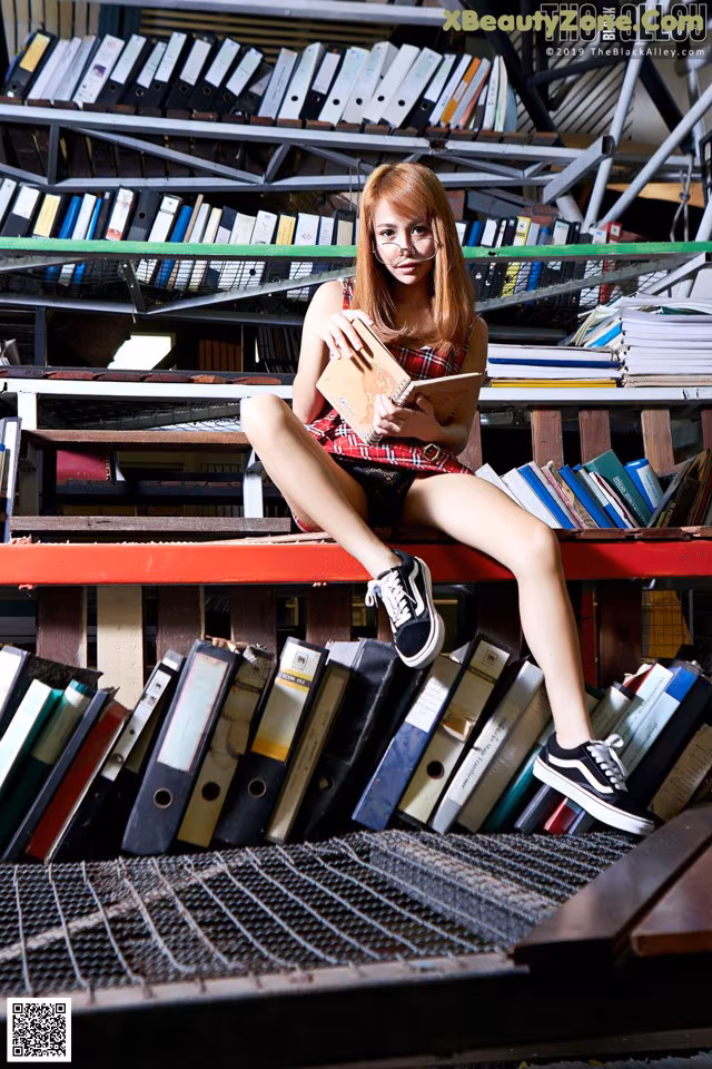 A woman sitting on top of a pile of books.