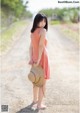 A woman in a pink dress holding a straw hat.