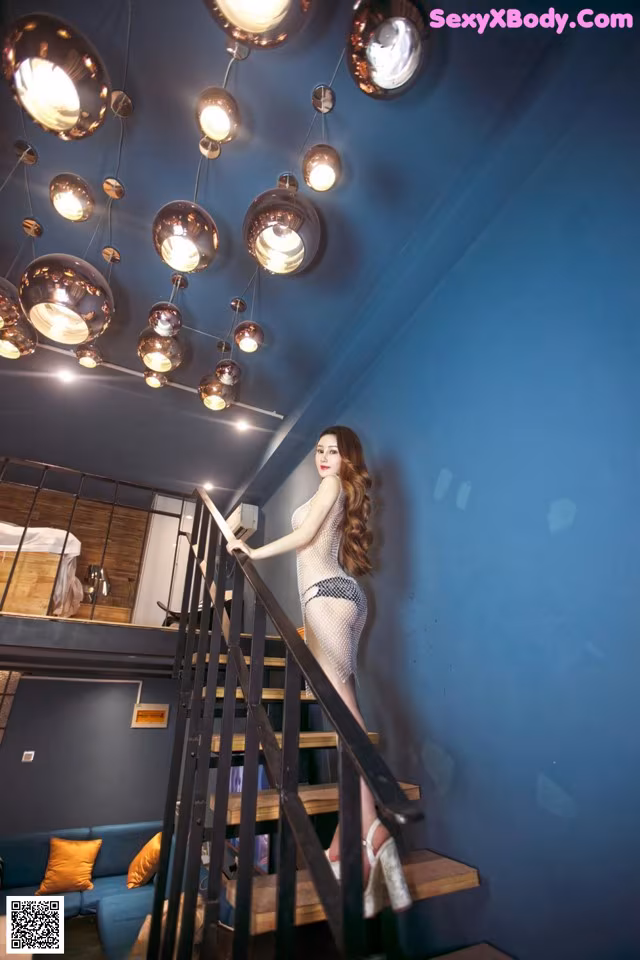 A woman in a fishnet dress is standing on the stairs.