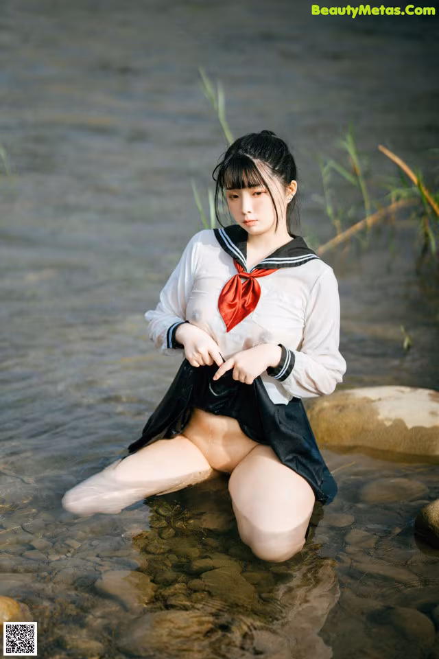 A woman in a sailor outfit sitting in the water.