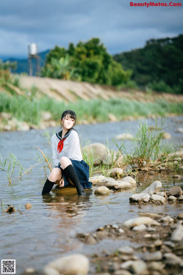 A woman sitting in the middle of a river.