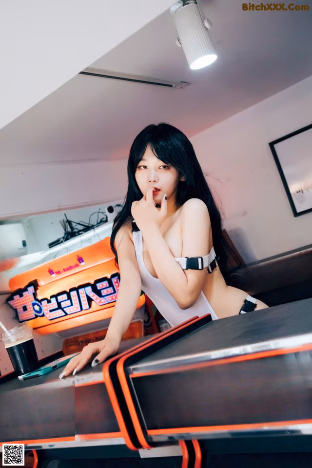 A woman sitting at a table in front of a video game machine.