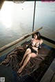 A woman in a black bikini sitting on a boat.