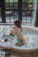 A naked woman sitting in a bathtub in a bathroom.