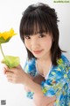 A young woman holding a yellow flower in her hand.