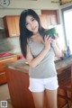 A woman holding a watermelon in a kitchen.