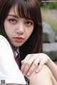 A woman with long brown hair and a white shirt.